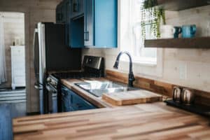 wood countertops and blue cabinets in cottage style kitchen in prefab cabin