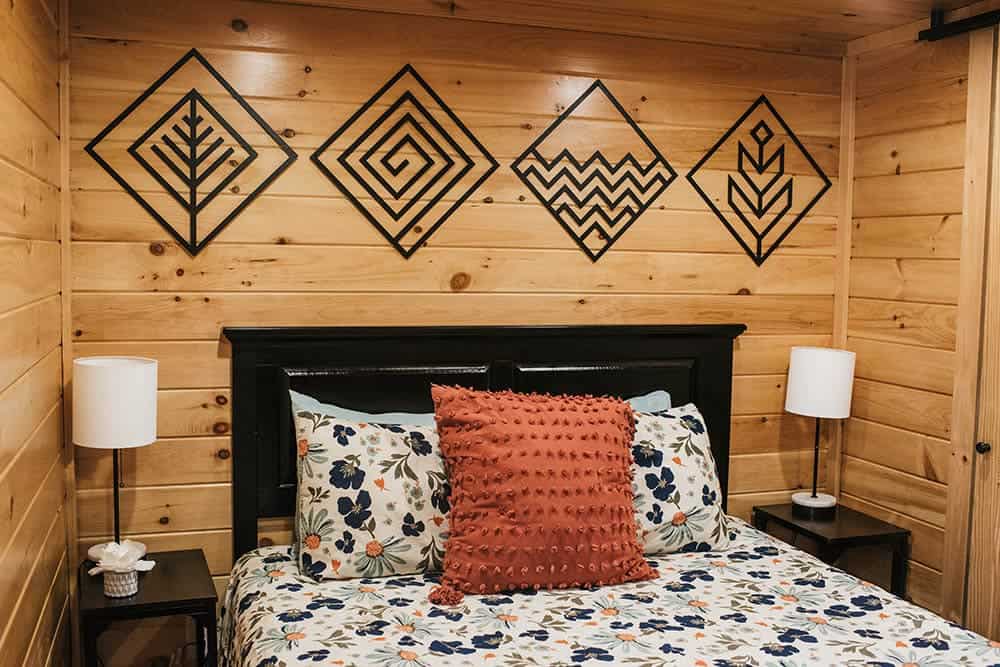 wood walls in bedroom with black accents and furniture in prefab log cabin