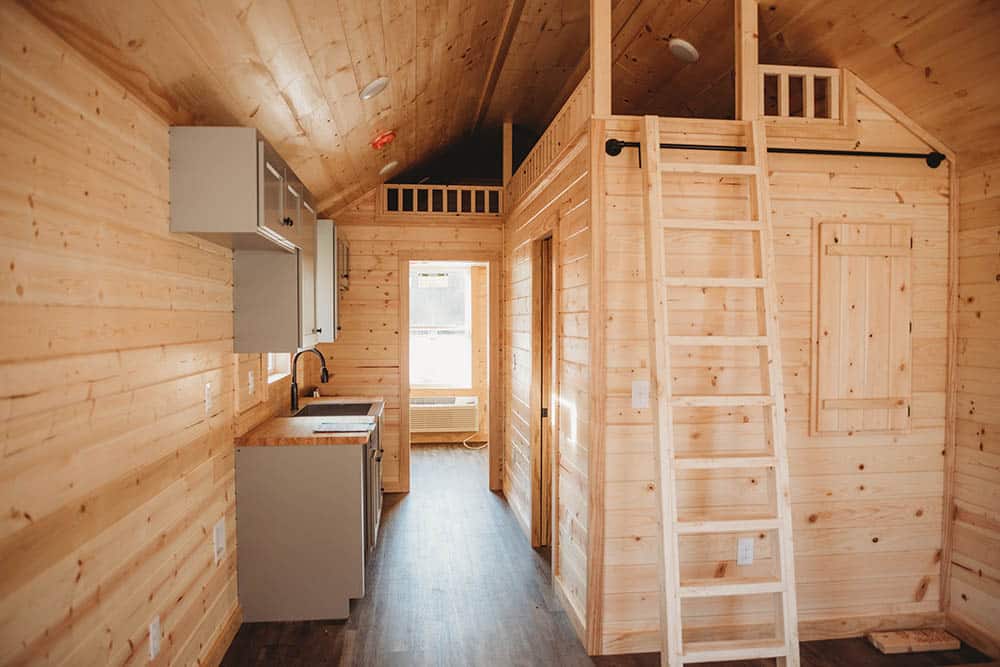 light colored wood in loft space and kitchen in modular log cabin