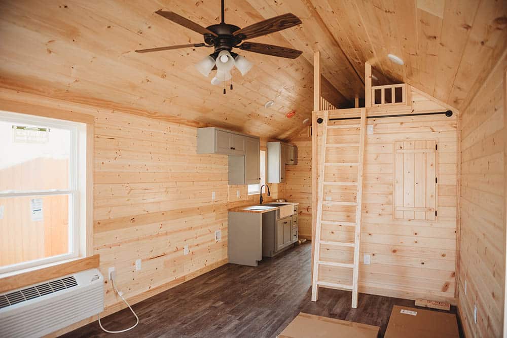 wood living space and ladder to loft in prefab log cabin