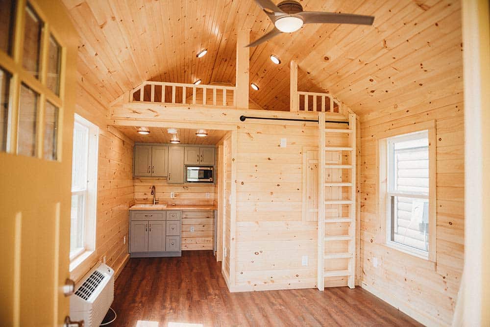 living space, kitchen, and loft space with wooden interior of prefab log cabin