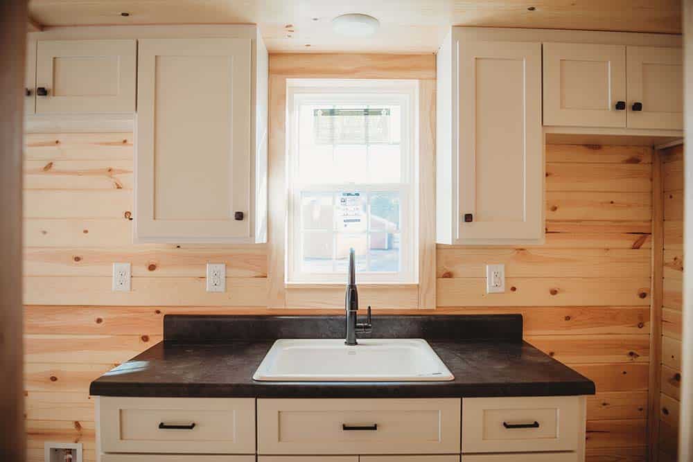 white cabinets and dark countertops with wood interior in modular log cabin