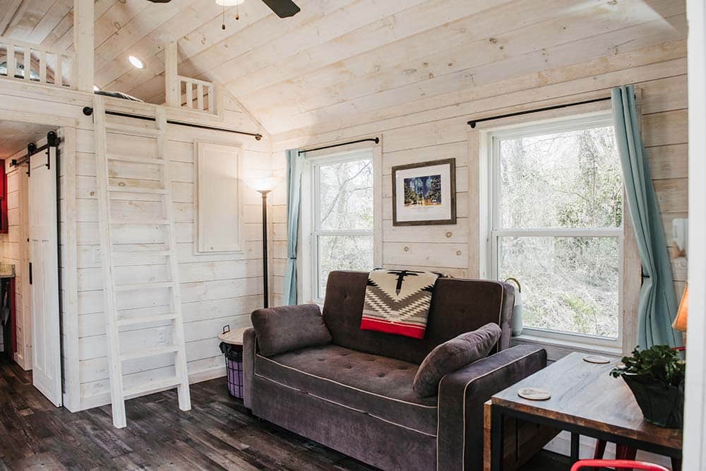 white wood interior living space and ladder to loft space in prefab tiny cabin
