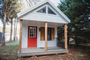 white exterior and wood accent modular cabin with red door